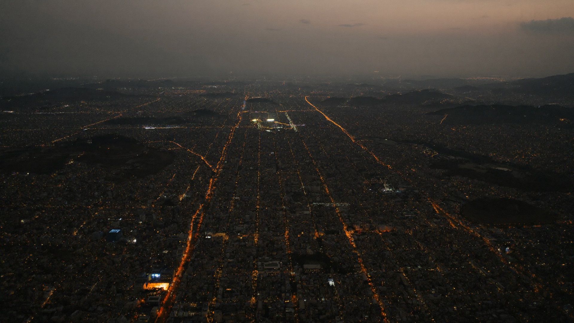 Aerial view of a west African city at dusk, streets traced in warm light